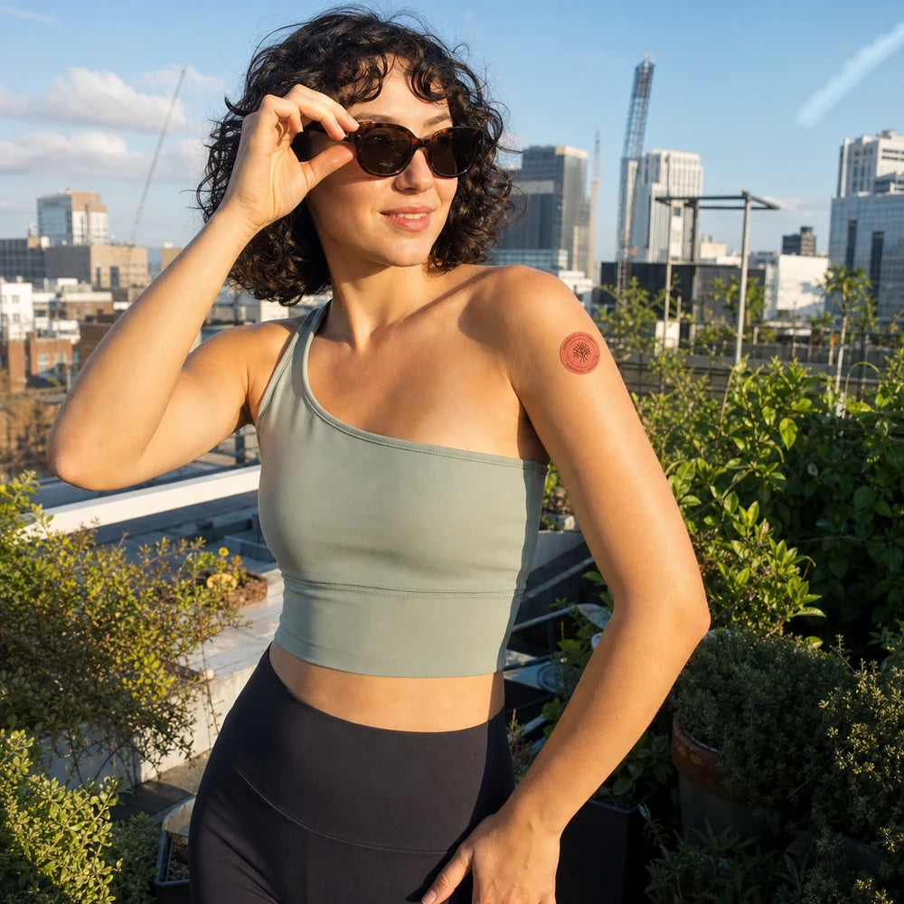 Eine Frau auf einer Dachterrasse trägt ein Elanessa Pflaster am Oberarm