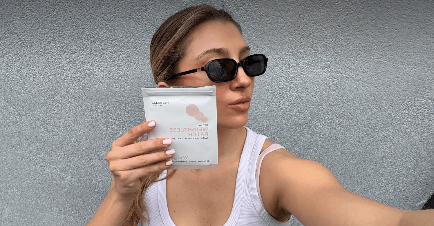A woman in sunglasses and a white tank top holds a white packet labeled Elanessa Berberine Patch.